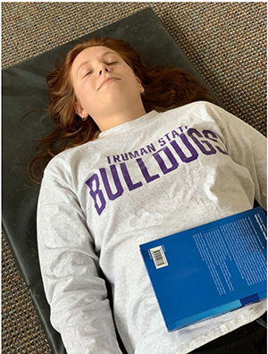 Person lying down with a book resting on the abdomen for breathing feedback